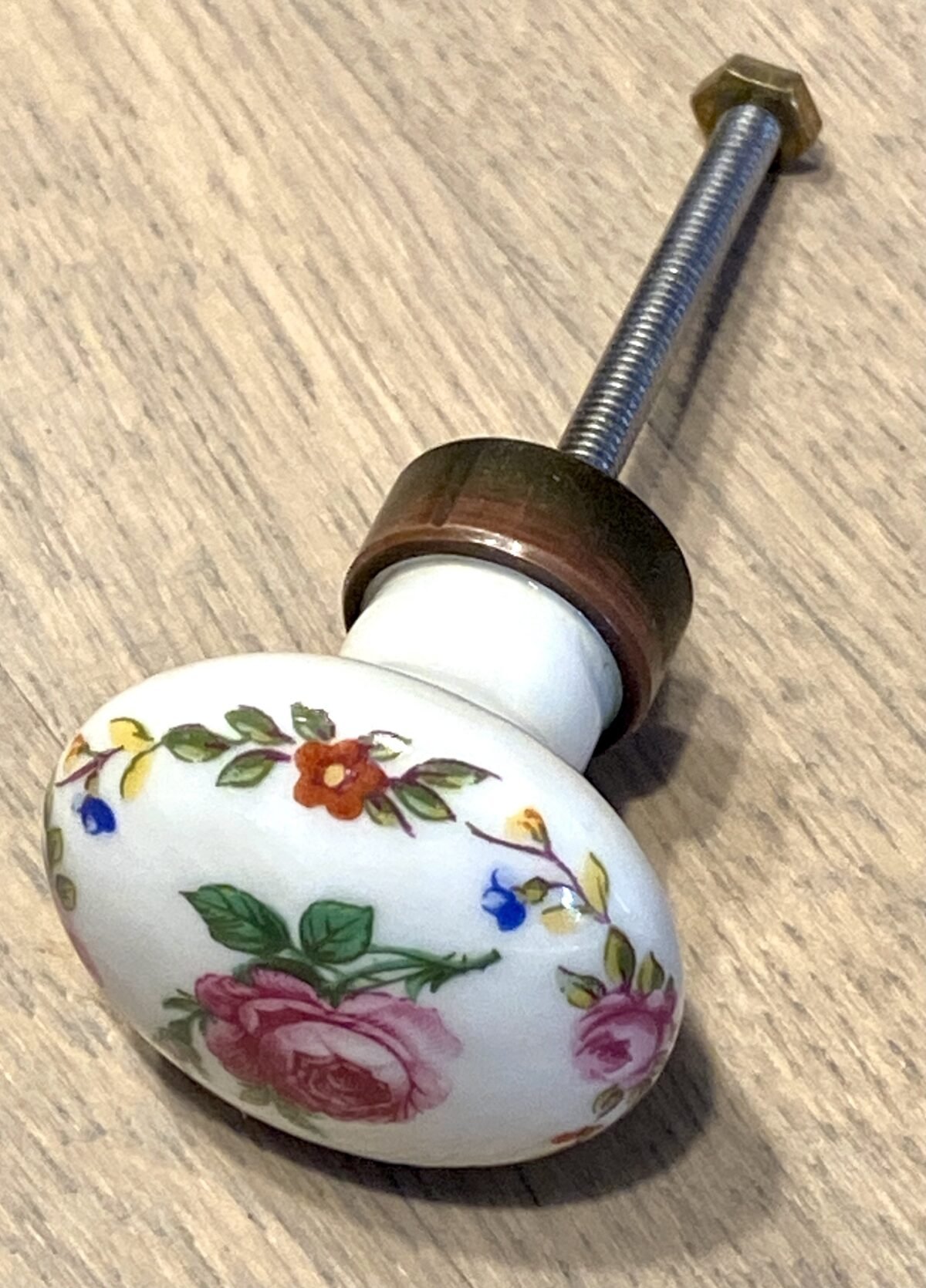 <p>Kastknopje, rond - porselein - met een décor van een roosje en bloemetjesrand</p> - Onbekend