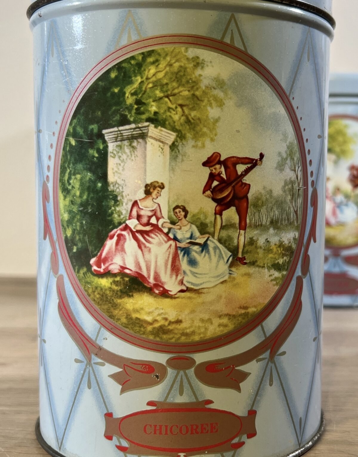 <p>Voorraadblik met deksel - uitvoering in metaal/blik - ongemerkt - opschrift CAFE - in blauwe uitvoering met afbeelding van 2 vrouwen en minstreel</p> - Brocante