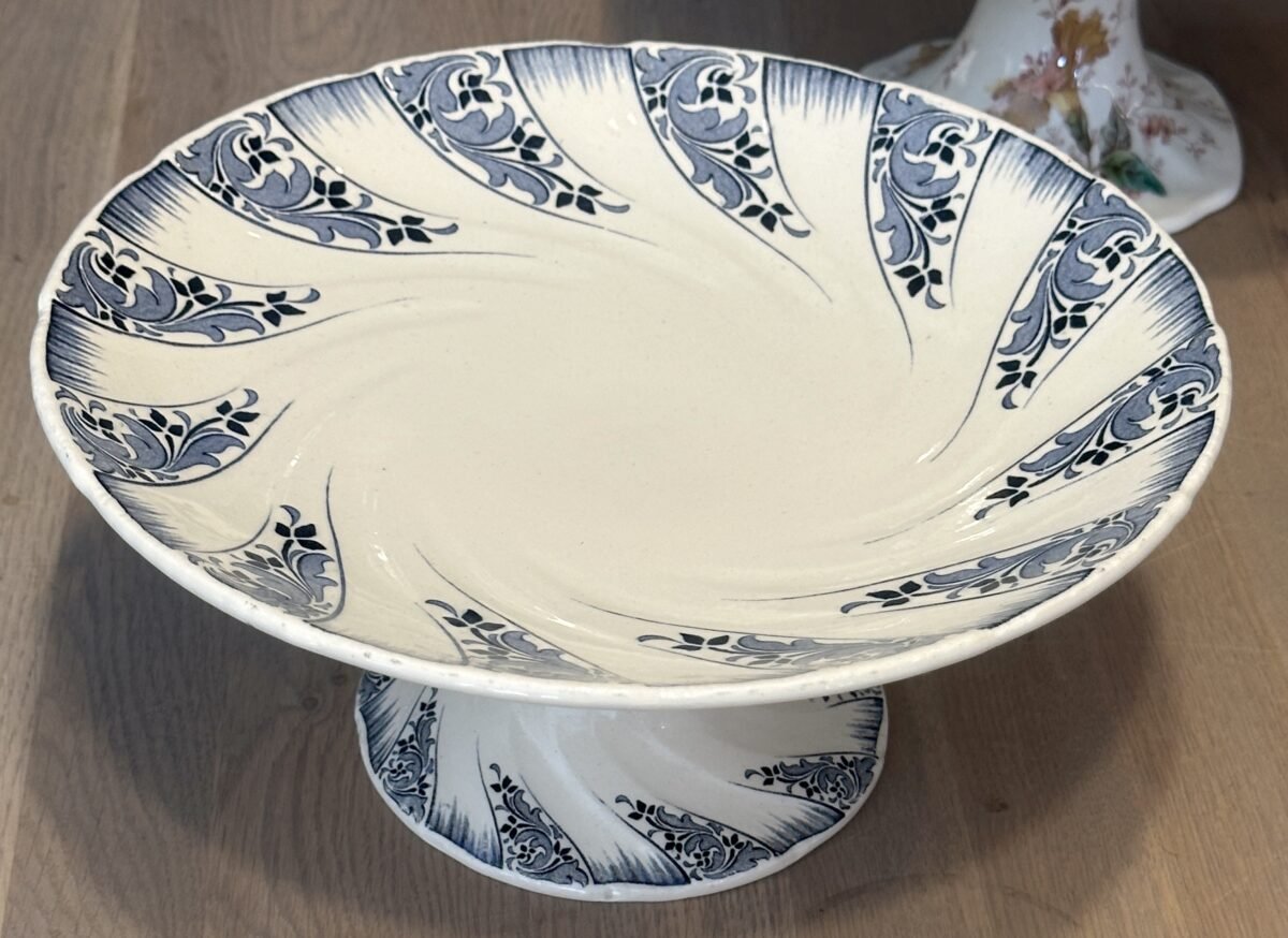 <p>Tazza / Schaal op middelhoge voet - Luneville- décor uitgevoerd in blauw met gestileerde bloemen en gegolfde rand</p> - Luneville