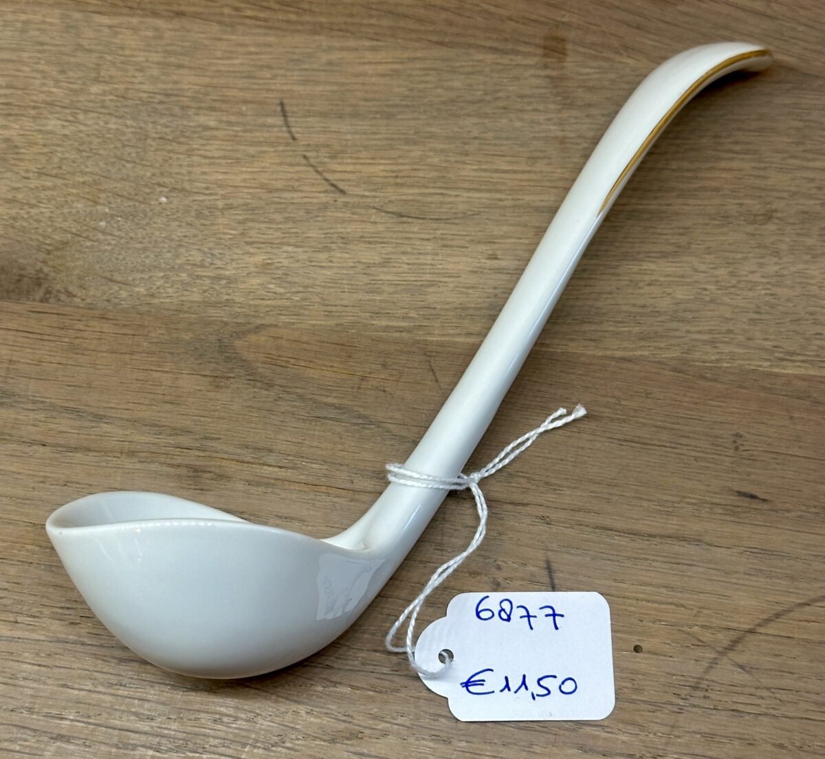 <p>Sauslepel / Lepel - ongemerkt - porselein uitgevoerd in wit met goudkleurige filets</p> - Onbekend