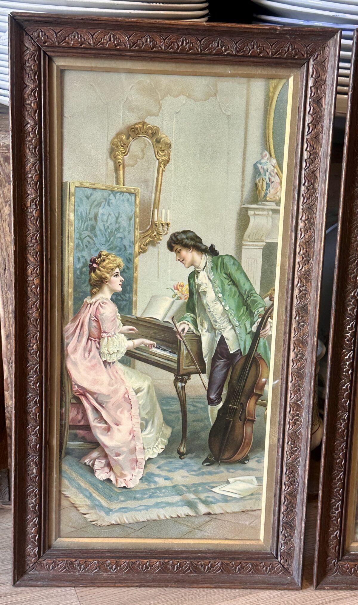 <p>Plaat in oblong houten lijst met afbeelding van een dame aan een klavecimbel/piano met staande man</p> - Brocante