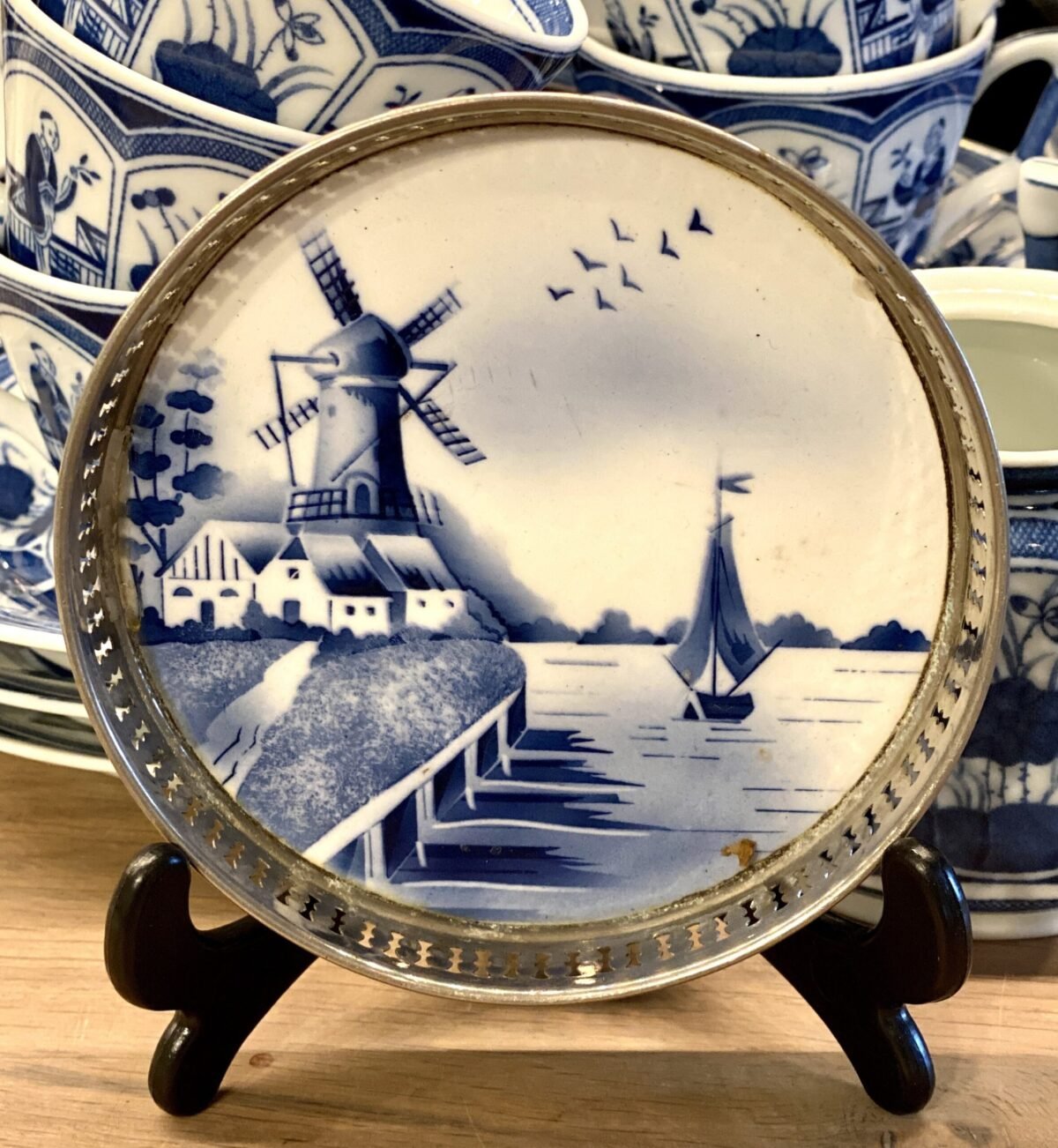 <p>Flesonderzetter / onderzetter - rond - met opstaande opengewerkte metalen rand - spuitdecor van molen, huisjes en zeilbootje</p> - Onbekend