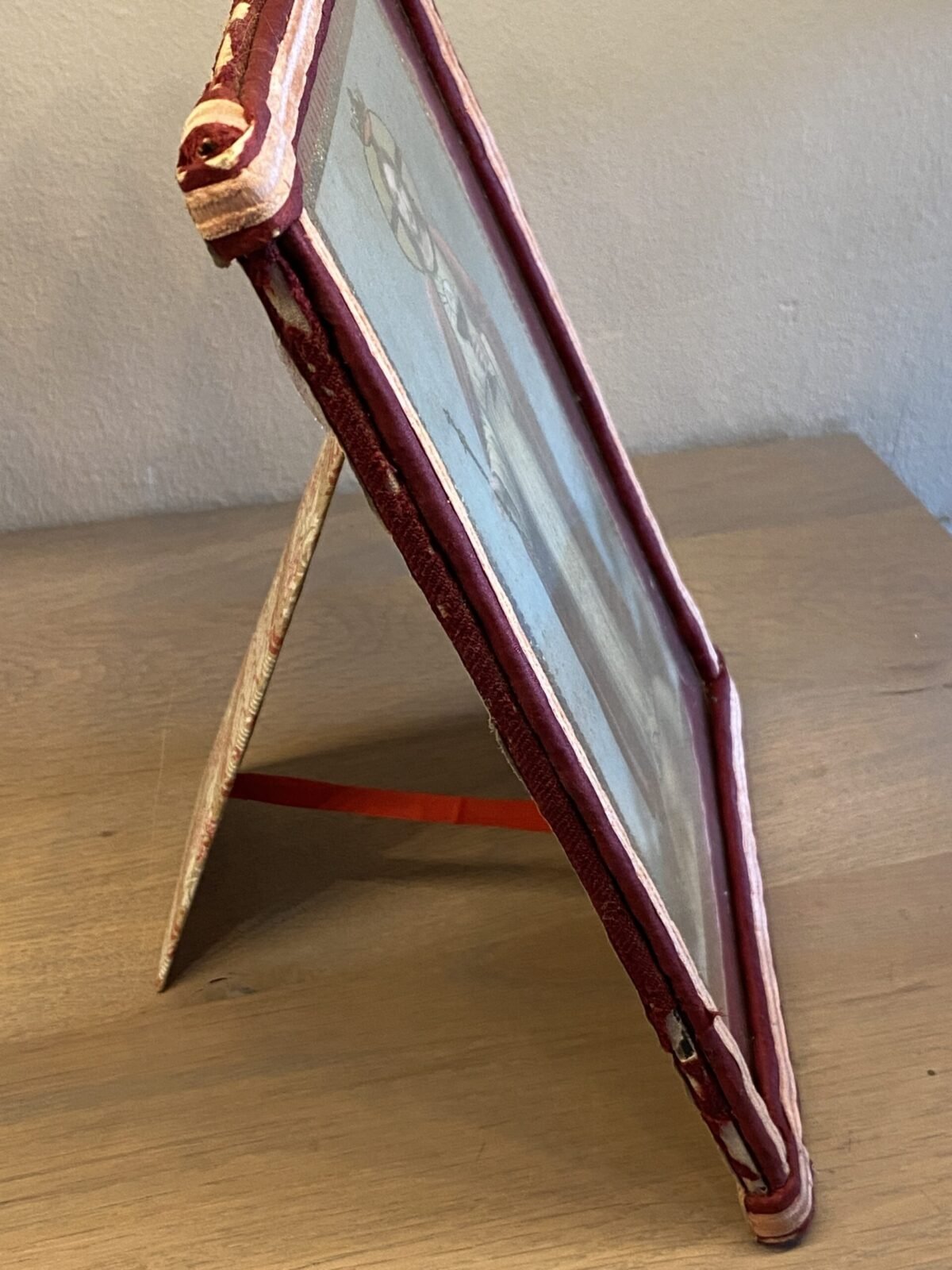 <p>Religieus plaatje in lijst (staand) - randen van rode en roze stof</p> - Brocante