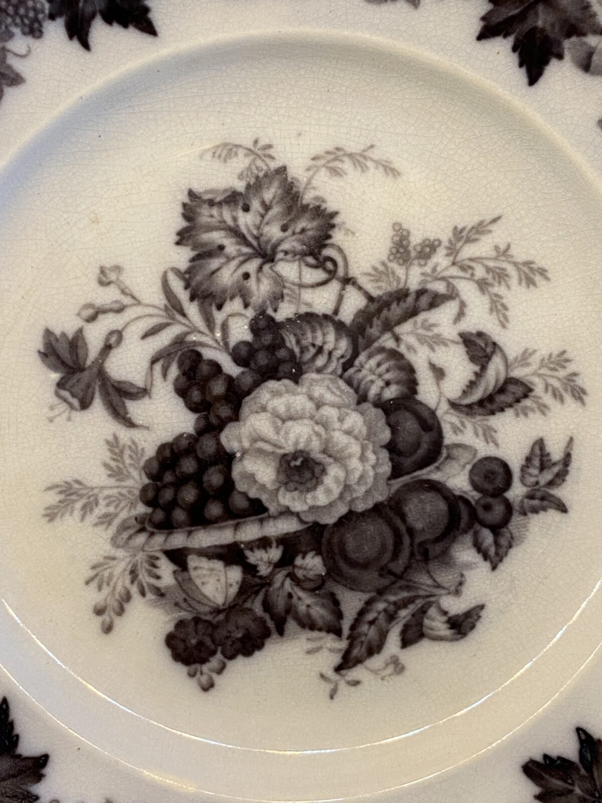 <p>Ontbijtbordje / breakfast plate / frukost tallrik - licht gegolfde rand - Rörstrand (Zweden / Sweden / Sverige) - décor druiven / grapes / druvor en ander fruit / frukt in vloeizwart / flow black / flytande svart</p> - Zweden